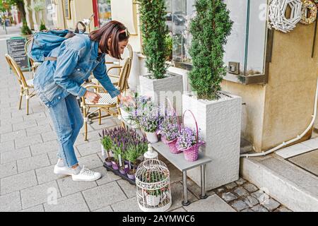 Un compratore della donna seleziona ed odora i bouquet prima dell'acquisto ad un negozio di fiori sulla strada Foto Stock