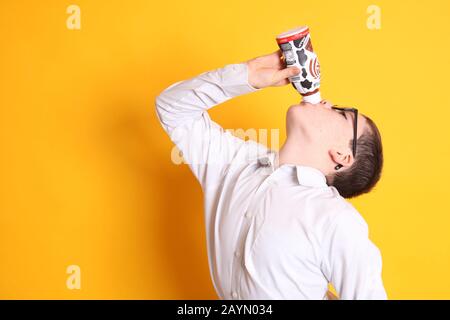 Un giovane ragazzo di età 8yrs beve una bottiglia di cioccolato Muller Frijj su sfondo giallo Foto Stock