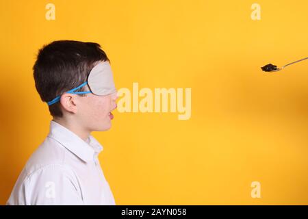 Prova del gusto alla cieca, ragazzo di 12 anni che degusta diversi alimenti bendati Foto Stock