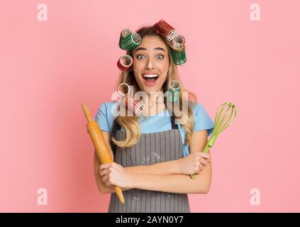 Sorpresa casalinga con curlers apre la bocca larga con shock Foto Stock