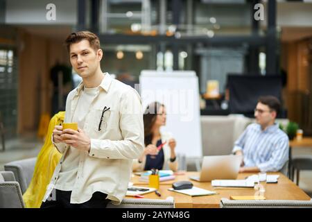 bell'uomo appoggiato sulla scrivania e guardando la fotocamera. primo piano. copiare lo spazio. sfondo sfocato Foto Stock
