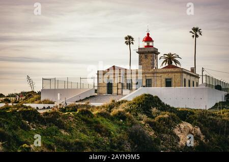 Il faro sulla punta che si affaccia scogliere Foto Stock