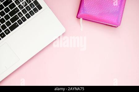 Tastiera per laptop in bianco e nero, blocco note rosa, su sfondo rosa. Spazio di copia. Disposizione piatta. Vista dall'alto. Foto Stock