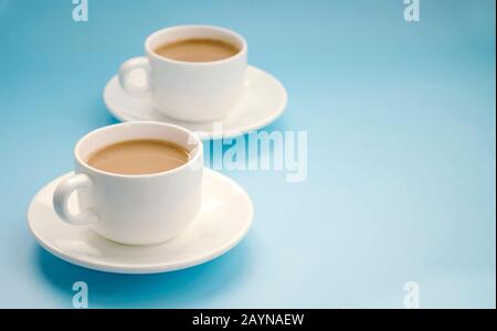 Due tazze di caffè bianco con latte, sfondo azzurro, vista laterale. Americano. Spazio di copia Foto Stock