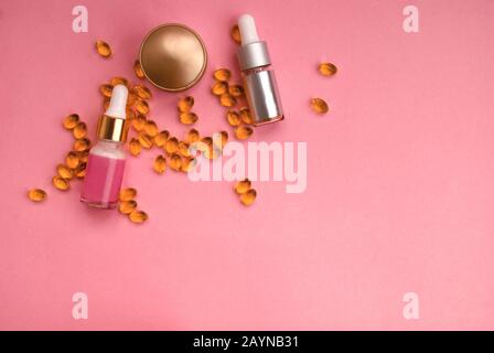 Flacone di crema con capsule di olio, siero cosmetico con pipetta su fondo rosa. Spazio per il testo. Disposizione piatta. Vista dall'alto Foto Stock