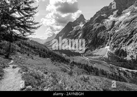 Il percorso escursionistico Tour du Mont Blanc attraverso le Alpi Italiane con un ghiacciaio su una montagna nella valle sullo sfondo Foto Stock