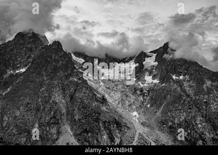 Un ghiacciaio su una cima di montagna e nuvole tempestose nelle Alpi italiane Foto Stock