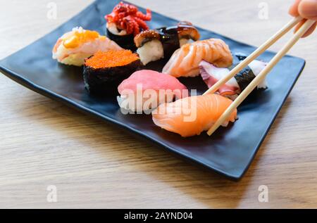 Salmone Sushi con chopstick e Nigiri Sushi set su piastre in argilla, piatto. Deliziosa cucina tradizionale giapponese, gustosi frutti di mare, ristorante concetto, foo Foto Stock