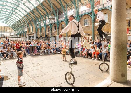 Bambini che guardano i pulcisti unicycle che si esibiscono a Covent Garden, Londra, Regno Unito Foto Stock