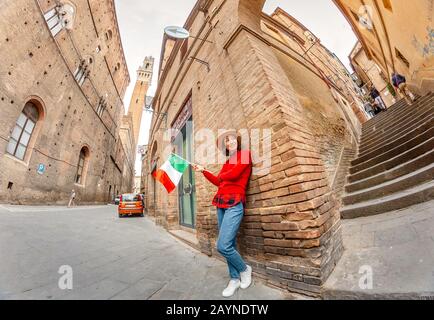 17 OTTOBRE 2018, SIENA, ITALIA: Donna viaggiatore con bandiera in strada stretta in Italia Foto Stock