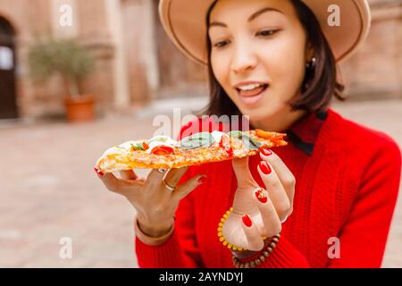 Donna felice che mangia pizza fetta in Italia, all'aperto. Viaggi in Europa e concetto di cibo italiano Foto Stock