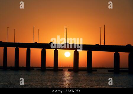 Silhouette di ponte sul mare contro il bel tramonto. Abu Dhabi, Emirati Arabi Uniti Foto Stock