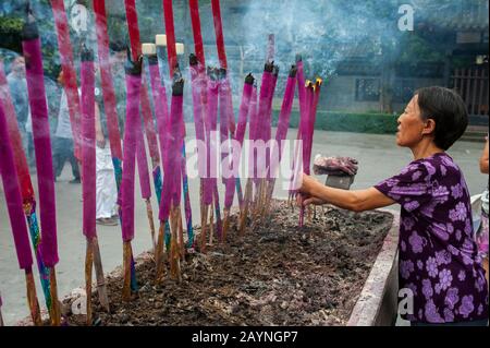 Una donna sta facendo offerte di incenso al Tempio Sanyi, al Monastero di Wu Hou a Chengdu, provincia di Sichuan in Cina. Foto Stock