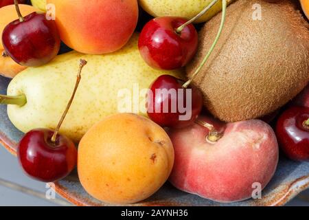 Ciliegie, pere, albicocche, kiwi e pesca in un recipiente Foto Stock