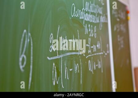 Formule matematiche su una scuola verde. L'iscrizione sulla lingua russa lo studio delle frazioni algebriche. Foto Stock