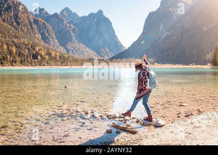 Felice giovane viaggiatore donna divertirsi su una costa di un lago Dobbiaco nelle Alpi Dolomiti, Italia Foto Stock