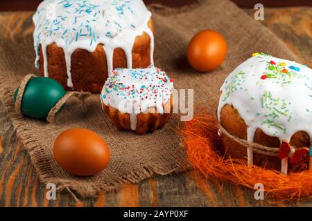Dolce di Pasqua fresco, cotto a casa e decorato con glassa dolce. Le uova bollite colorate si trovano sul tavolo come elemento della vacanza di Pasqua. Artificiale Foto Stock