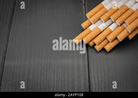 Set di filtri per sigarette di tabacco allineati nell'angolo in alto a destra su un legno grigio Foto Stock