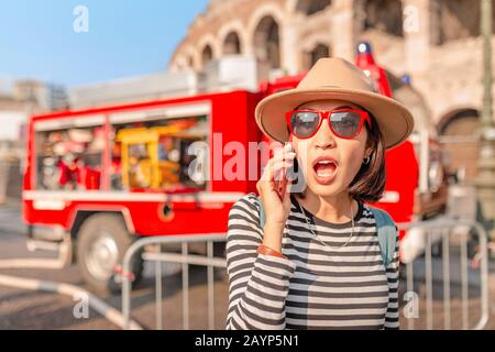 donna con uno smartphone chiamata emergenza 911 o 112 numero sullo schermo in background del reparto antincendio motore camion Foto Stock