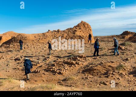 Turisti alla ricerca di fossili di dinosauri presso le scogliere fiammeggianti nel deserto del Gobi vicino a Bulgan, nella Mongolia meridionale, dove erano importanti fossili di dinosauri Foto Stock