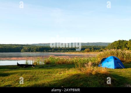 tenda sulla riva di un bellissimo lago su uno sfondo di cielo blu Foto Stock