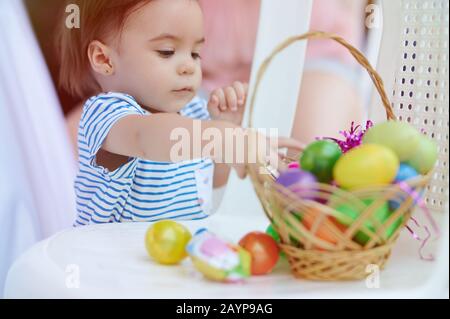 Bambina piccola cute con cesto di uova di pasqua sul cortile della casa Foto Stock