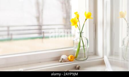 decorazione minimalistica di pasqua su campanelli di pasqua a daffodils in vecchio edificio uova di pasqua su davanzale sfondo chiaro, con spazio copia Foto Stock