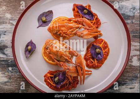 Vista dall'alto gamberi bolliti su un piatto. Delicatezza con salsa al peperoncino, basilico e capperi. Cucina gourmet Foto Stock