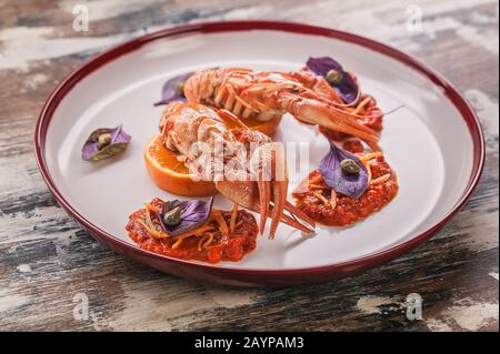 Gamberi bolliti. Delicatezza con salsa al peperoncino, basilico e capperi su un piatto. Cucina gourmet Foto Stock