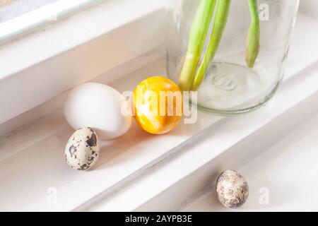 decorazione minimalistica di pasqua su campanelli di pasqua a daffodils in vecchio edificio uova di pasqua su davanzale sfondo chiaro, con spazio copia Foto Stock