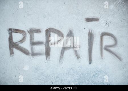 Immagine di fondo della parola DI RIPARAZIONE su muro di cemento in casa in costruzione, copia spazio Foto Stock