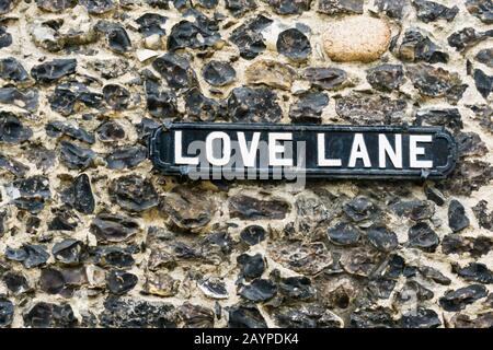 Un vecchio stile segno di strada in metallo per Love Lane su un muro di selce nella città vecchia di Margate. Foto Stock