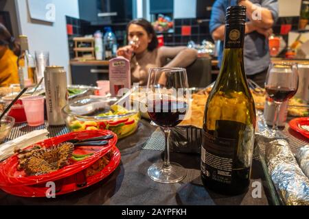 Cibo, bevande, bicchieri, bottiglia di vino, piatti di plastica su un tavolo a buffet a una festa. Foto Stock