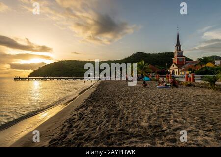 Martinica, Francia - 18 agosto 2019: Petite Anse d'Arlet villaggio al tramonto, con la chiesa di Saint Henri e pontone. Foto Stock