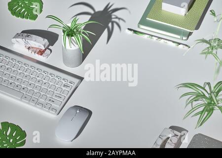 Sfondo concettuale con moderni accessori da ufficio in bianco, verde menta e marmo. Proiezione isometrica, layout geometrico con foglie monstera. Notebook, Foto Stock