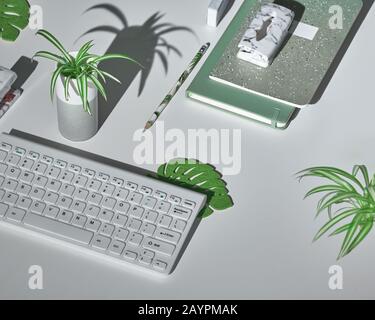 Sfondo concettuale con moderni accessori da ufficio in bianco, verde menta e marmo. Proiezione isometrica, layout geometrico con foglie tropicali. Notebook, Foto Stock