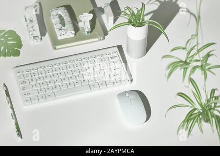 Concept spazio di lavoro sullo sfondo con moderni accessori da ufficio in bianco, verde, marmo. Proiezione isometrica, disposizione geometrica con foglie esotiche. Notebook, st Foto Stock