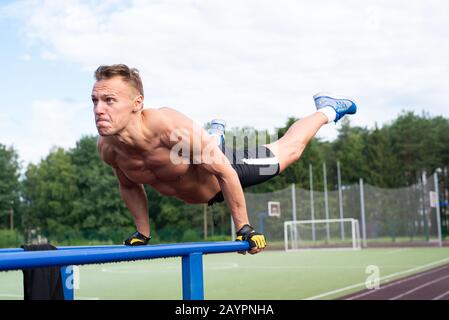 Un uomo muscoloso viene strizzato dalle barre parallele. Foto Stock