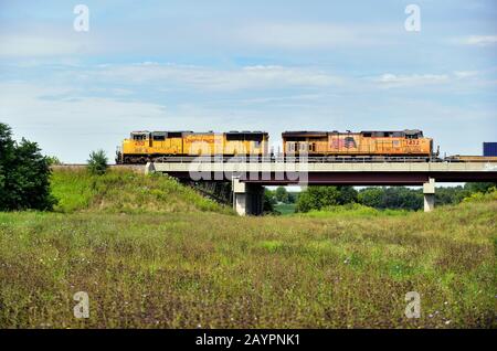 Lafox, Illinois, Stati Uniti. Un treno merci dell'Unione del Pacifico, guidato da due unità motrici, passa sopra un ponte. Foto Stock