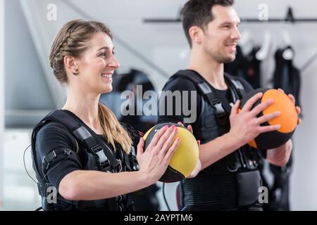 Adatta donna e uomo con palla in palestra wireless ems esercizio Foto Stock