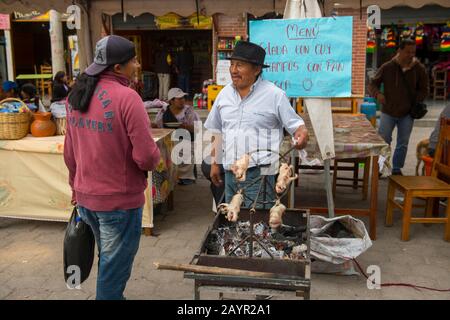 Scena di strada con un uomo barbequing cavie in un piccolo villaggio vicino alla città di Otavalo nelle Highlands dell'Ecuador vicino Quito. Foto Stock