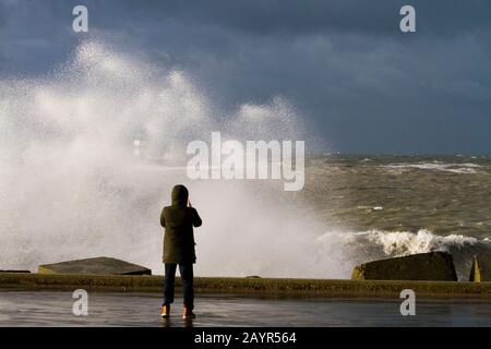 Uomo che scatta foto del faro sul molo durante la tempesta, Olanda, Scheveningen Foto Stock