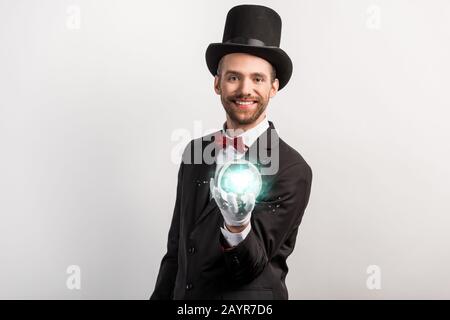 mago professionista che tiene palla magica blu, isolato su grigio Foto Stock