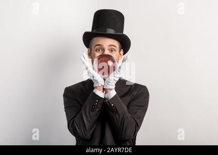 mago professionista che tiene palla magica, isolato su grigio Foto Stock