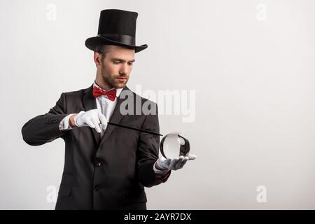 mago professionista con bacchetta e palla magica, isolato su grigio Foto Stock
