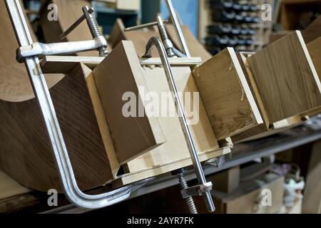 Pezzi di legno serrati che si collegano con morsetto speciale, pezzi di legno nell'officina di carpenteria Foto Stock