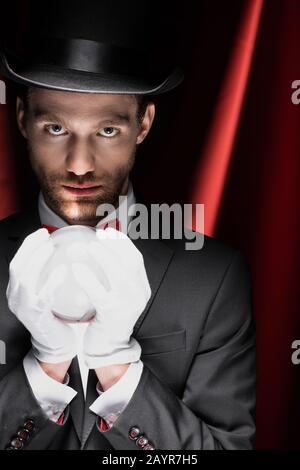 mago professionista che tiene palla magica in circo con tende rosse Foto Stock