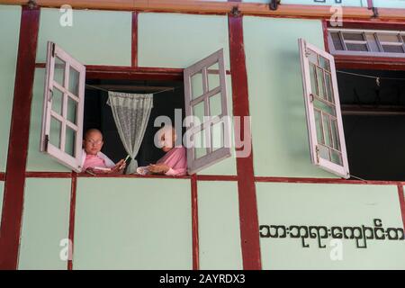 Giovani suore che guardano fuori dalla loro finestra dormitorio a Zayertheingi, un nunnery buddista a Sagaing, una città fuori Mandalay, Myanmar. Foto Stock