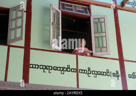 Una giovane suora alla finestra del suo dormitorio a Zayertheingi, un nunnery buddista a Sagaing, una città al di fuori di Mandalay, Myanmar. Foto Stock