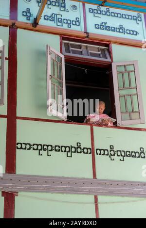 Una giovane suora alla finestra del suo dormitorio a Zayertheingi, un nunnery buddista a Sagaing, una città al di fuori di Mandalay, Myanmar. Foto Stock